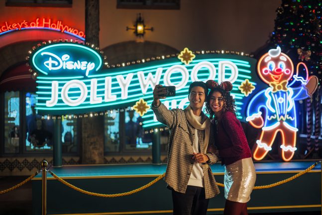 Guests pose in front of Disney Jollywood Nights marquee
