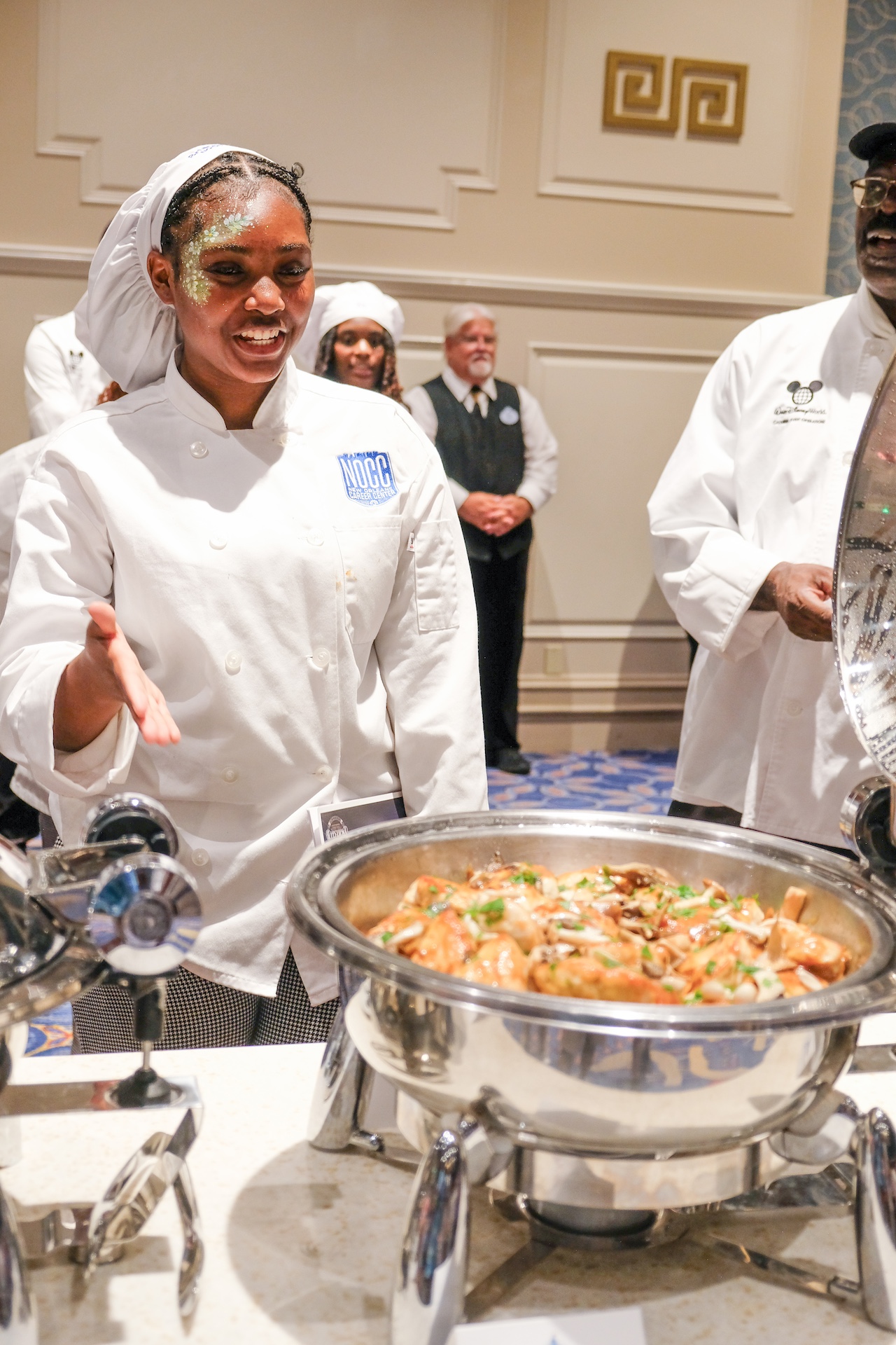One of the visiting aspiring chefs showcases a dish to her fellow tripmates and members of the Disney culinary team.