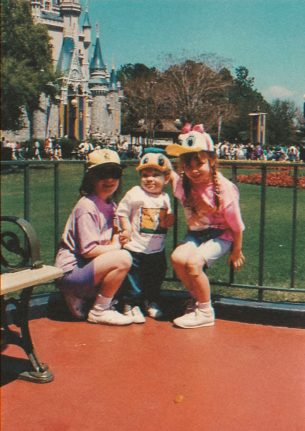 Jeffrey in an old photo, smiling in front of Cinderella Castle as a child and wearing a Donald hat