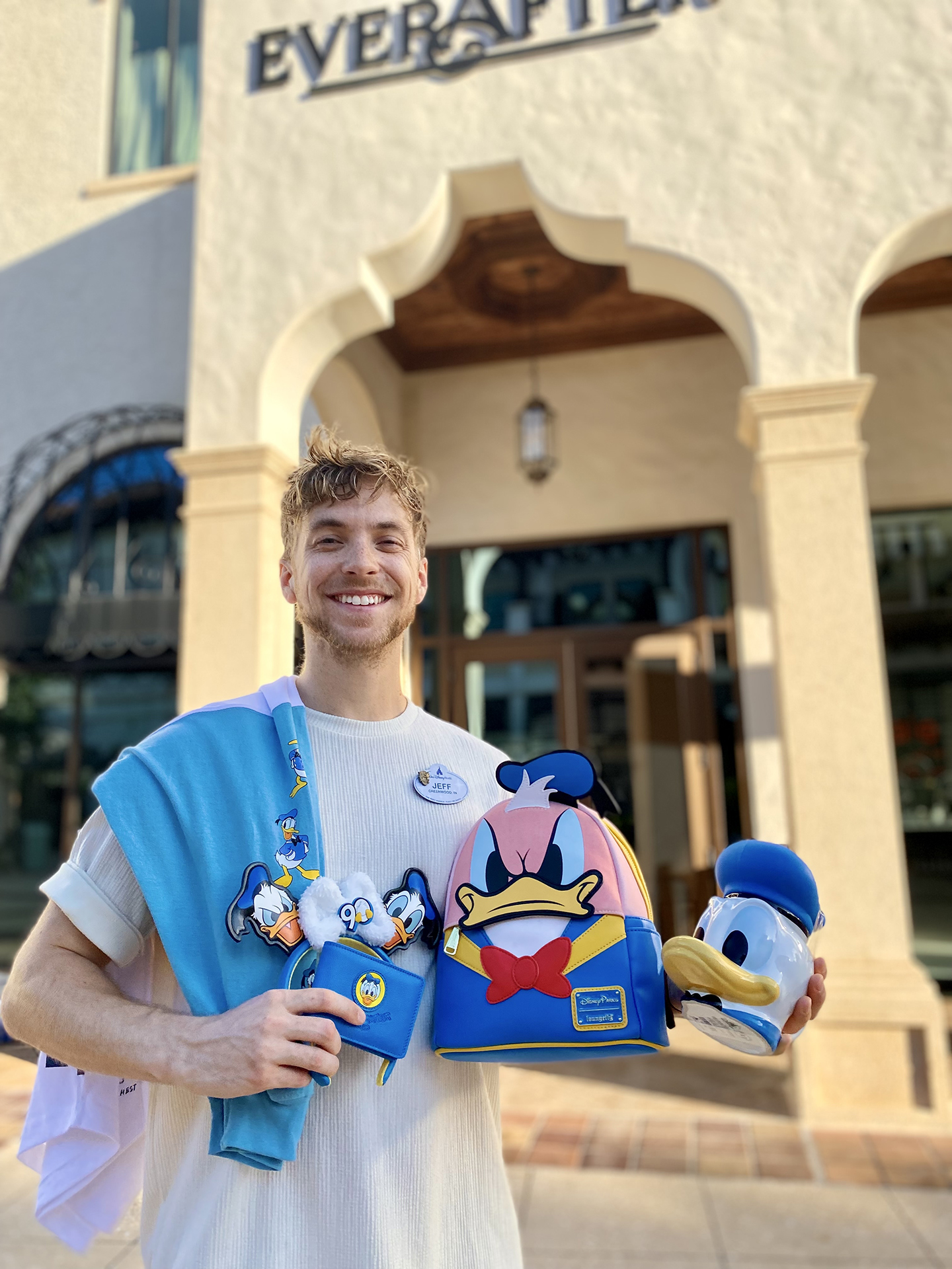 Jeffrey smiles in front of Disney Ever After holding Donald Duck 90 merchandise