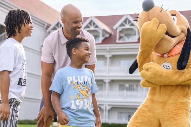 A family smiles with Pluto at Disney's Grand Floridian Resort