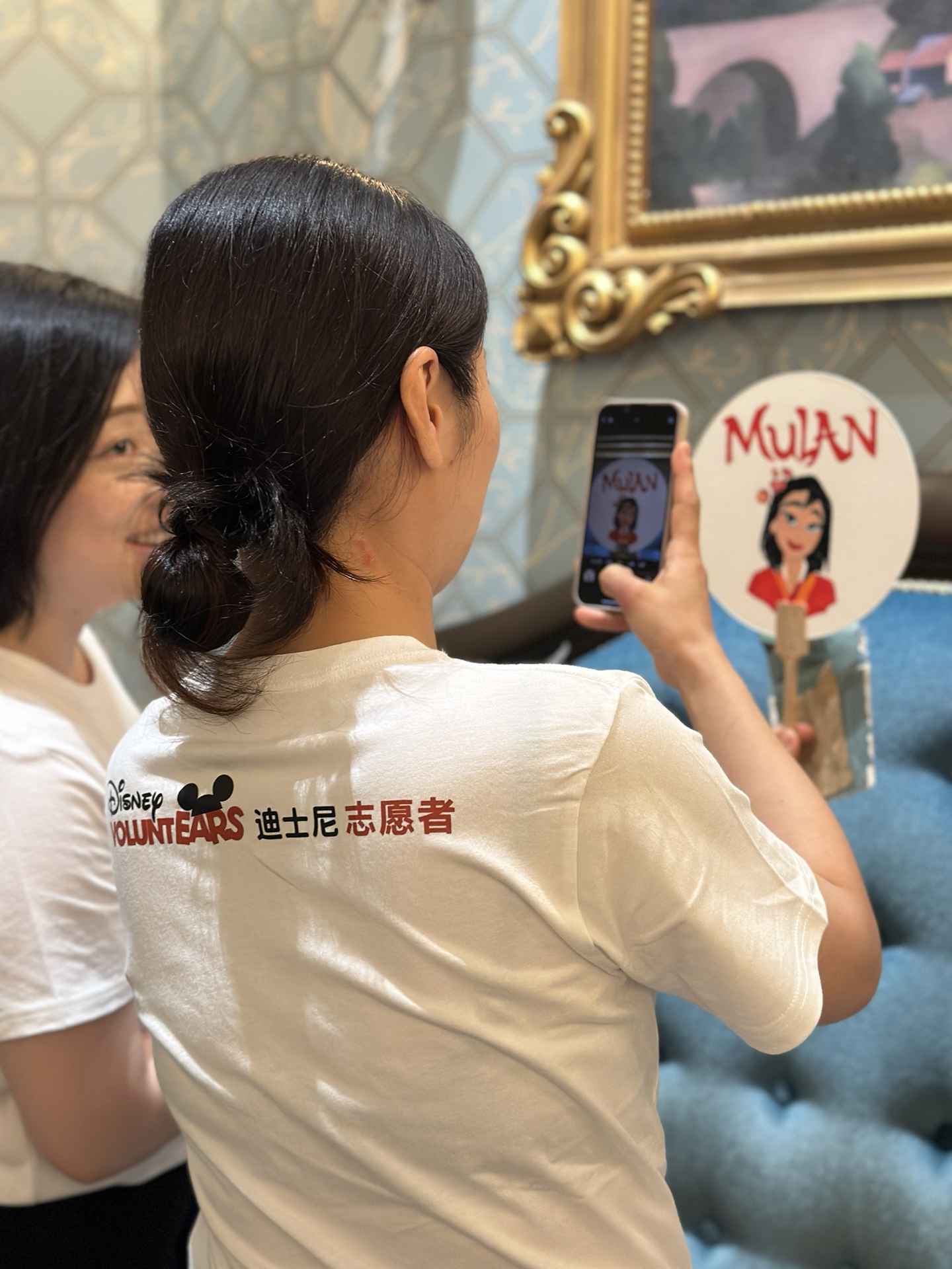 A VoluntEAR takes a picture of Xuanxuan's calligraphy on a fan