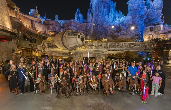 Wish families and volunteers pose in a group photo in Star Wars: Galaxy's Edge