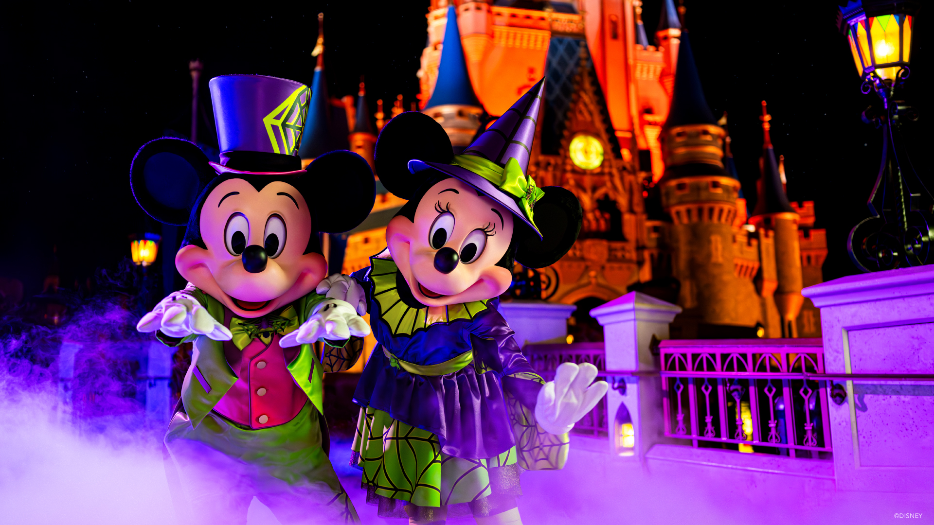 Mickey and Minnie pose in their Halloween outfits in front of Cinderella Castle