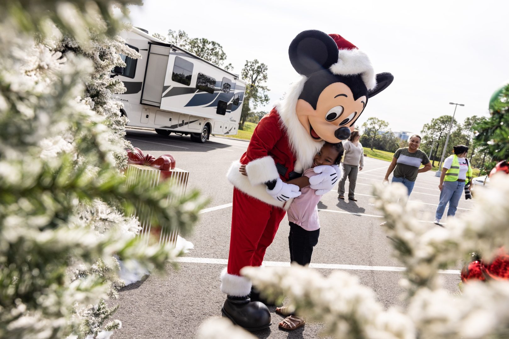 Mickey Mouse in holiday outfit hugging a child