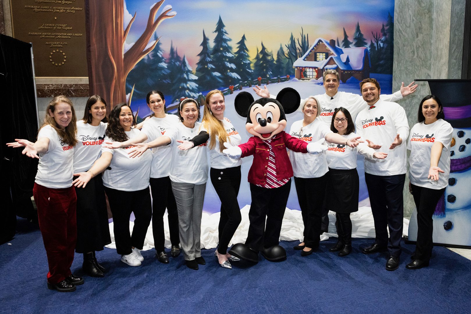 Mickey Mouse poses with Disney VoluntEARS