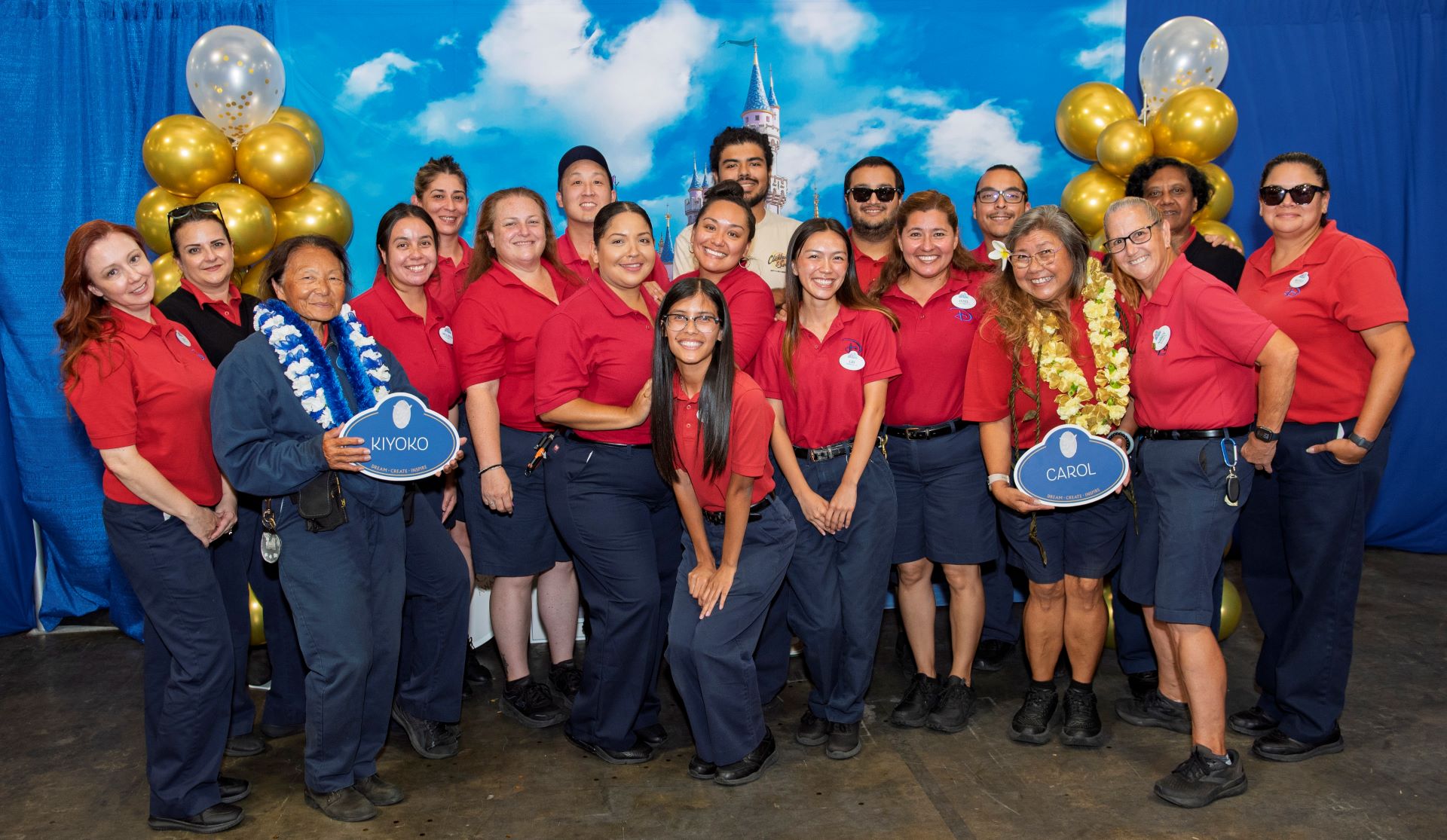 Group of smiling Disneyland employees in red shirts, celebrating Legacy Award recipients.