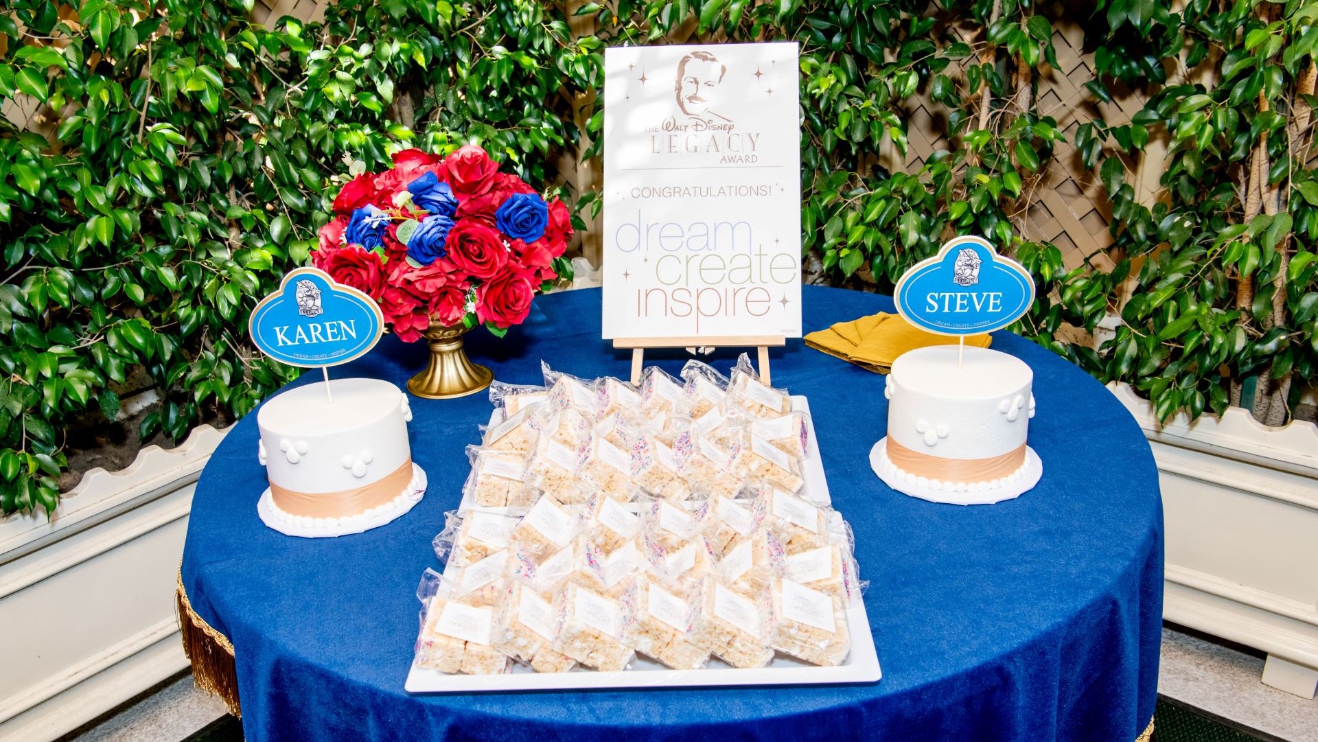 Table set with treats, a cake, and a floral arrangement for an award event.