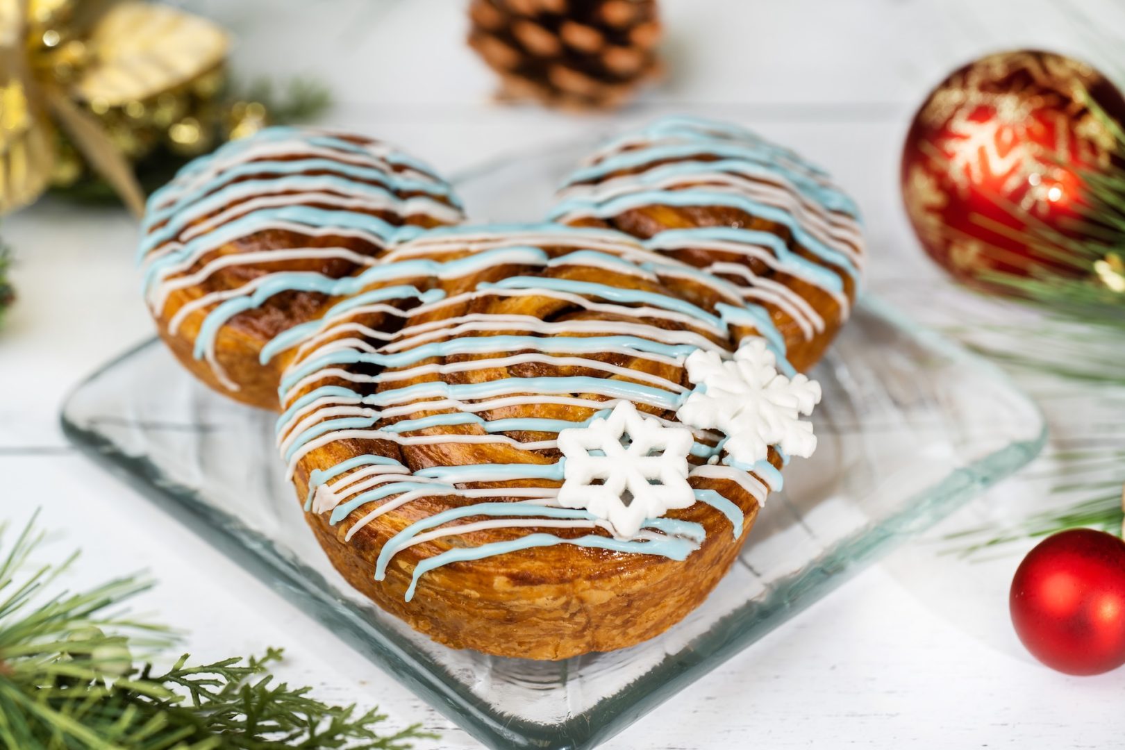 Cinnamon roll decorated with blue icing and snowflake accents on a festive plate.