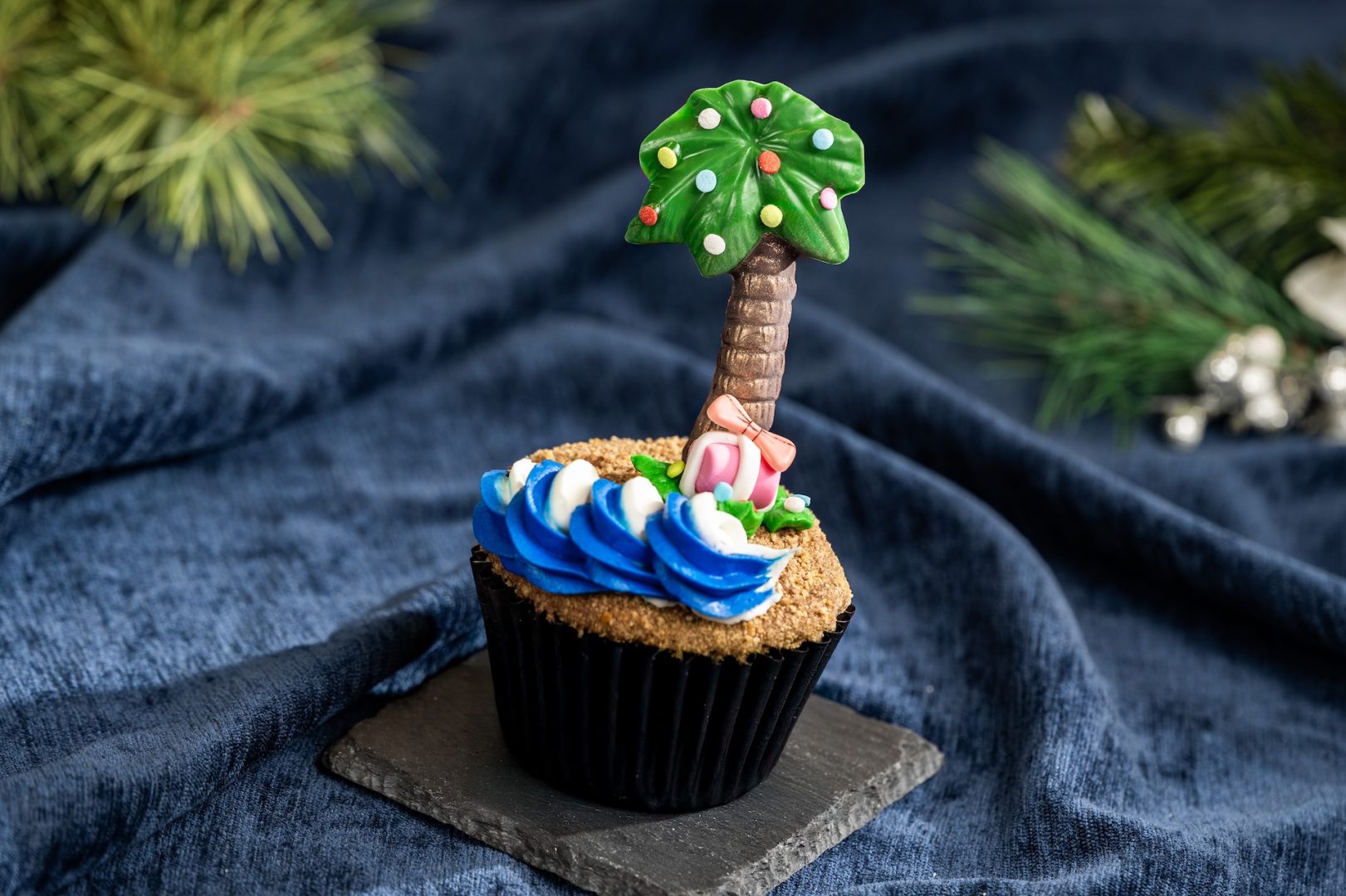 Colorful cupcake topped with a palm tree decoration and blue frosting.
