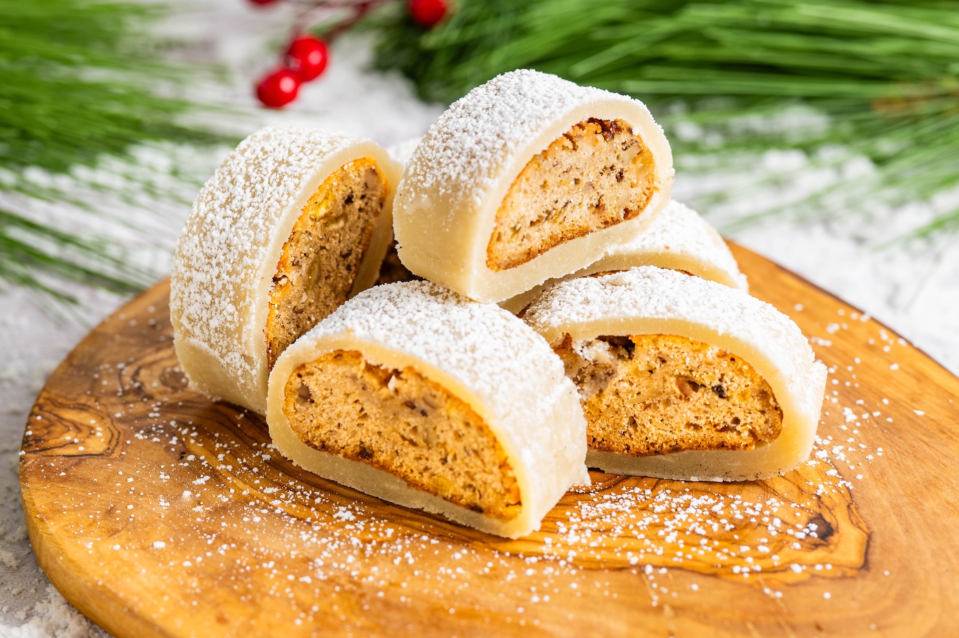 Four stollen bites dusted with powdered sugar on a wooden board.