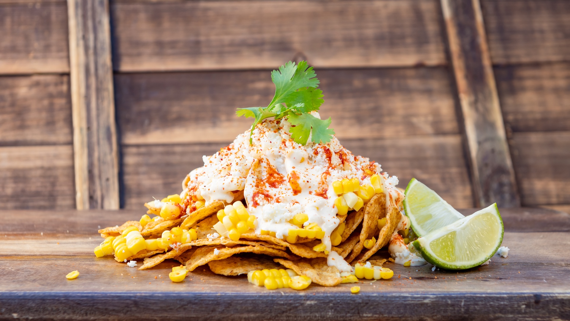 Esquites Loaded Chips: Chile-lime chips smothered in corn kernels, cotija cheese, chile-lime seasoning, and crema