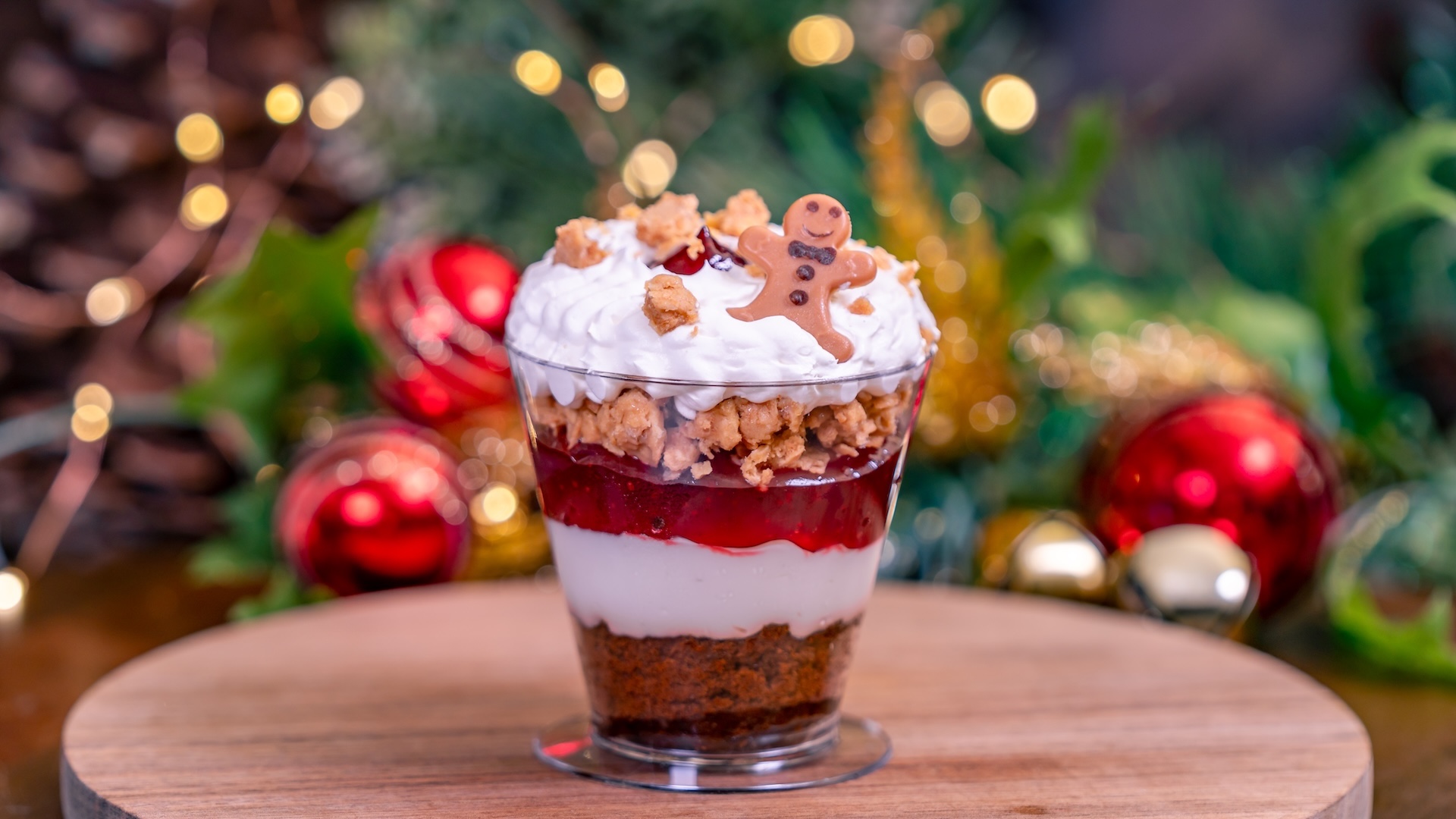 Gingerbread-Cranberry Cheesecake Trifle: Layers of gingerbread cake, cheesecake, and cranberry compote topped with gingerbread crunch, white chocolate mousse, and a mini gingerbread man 