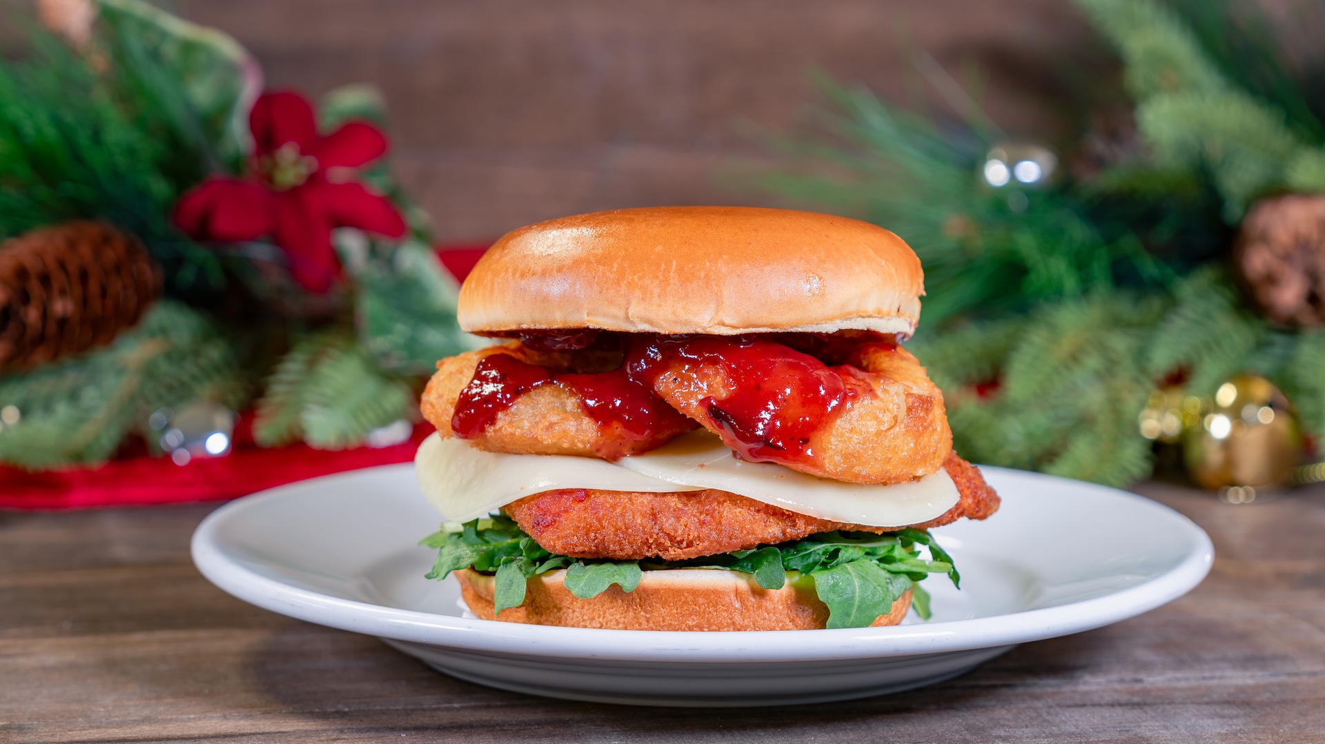 Merry Cranberry Crispy Chicken Sandwich: Fried chicken sandwich with cranberry-orange marmalade BBQ sauce, provolone, onion rings, and arugula served on a toasted brioche bun with your choice of Cuties Mandarin Orange or French fries  
