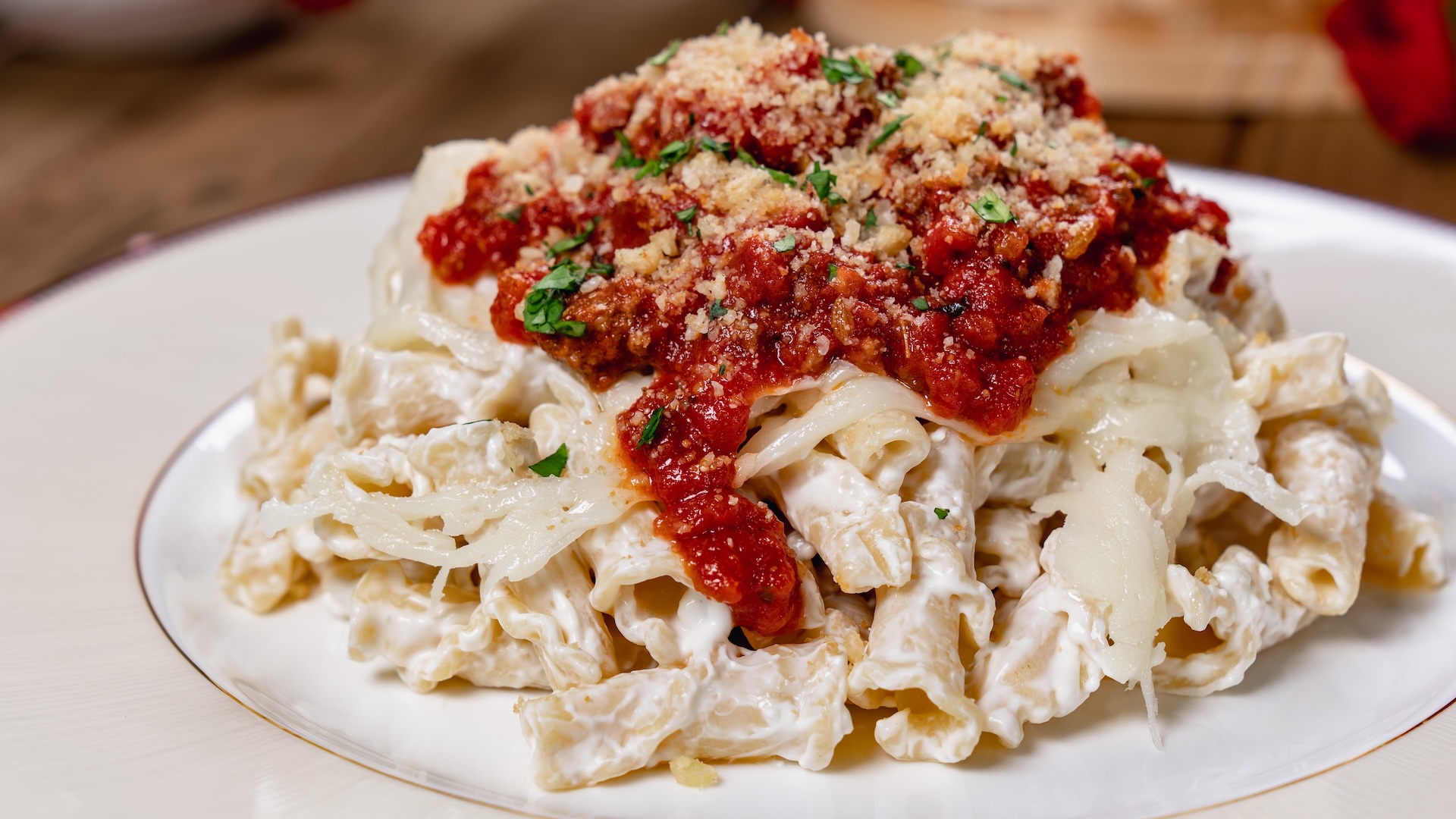 Claw-sagna Pasta: Campanelle pasta tossed in ricotta and mozzarella sauce, topped with bolognese sauce and garnished with toasted breadcrumbs, parmesan, and basil 