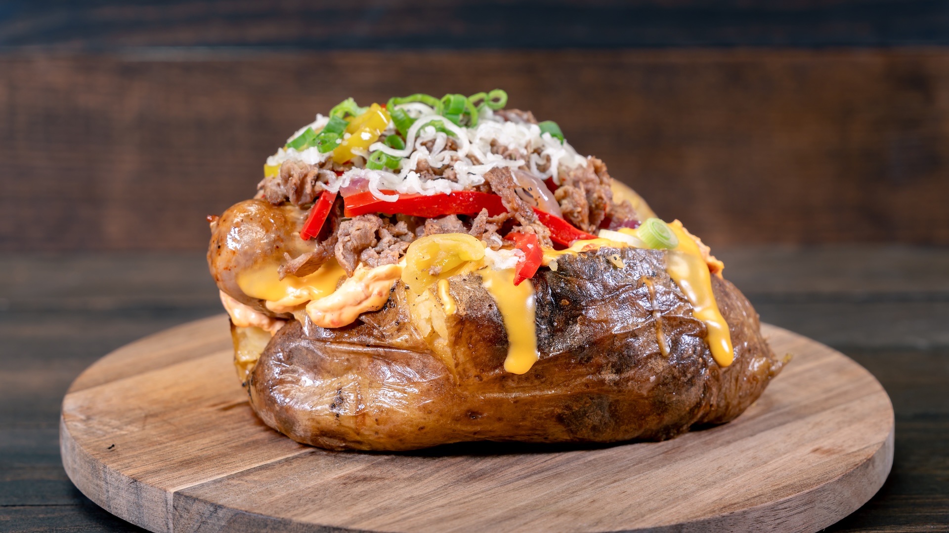 Philly Cheese Potato: Baked potato filled with Italian sausage, thinly sliced steak, bell peppers, pepperoncini, cheese sauce, and cherry pepper spread 