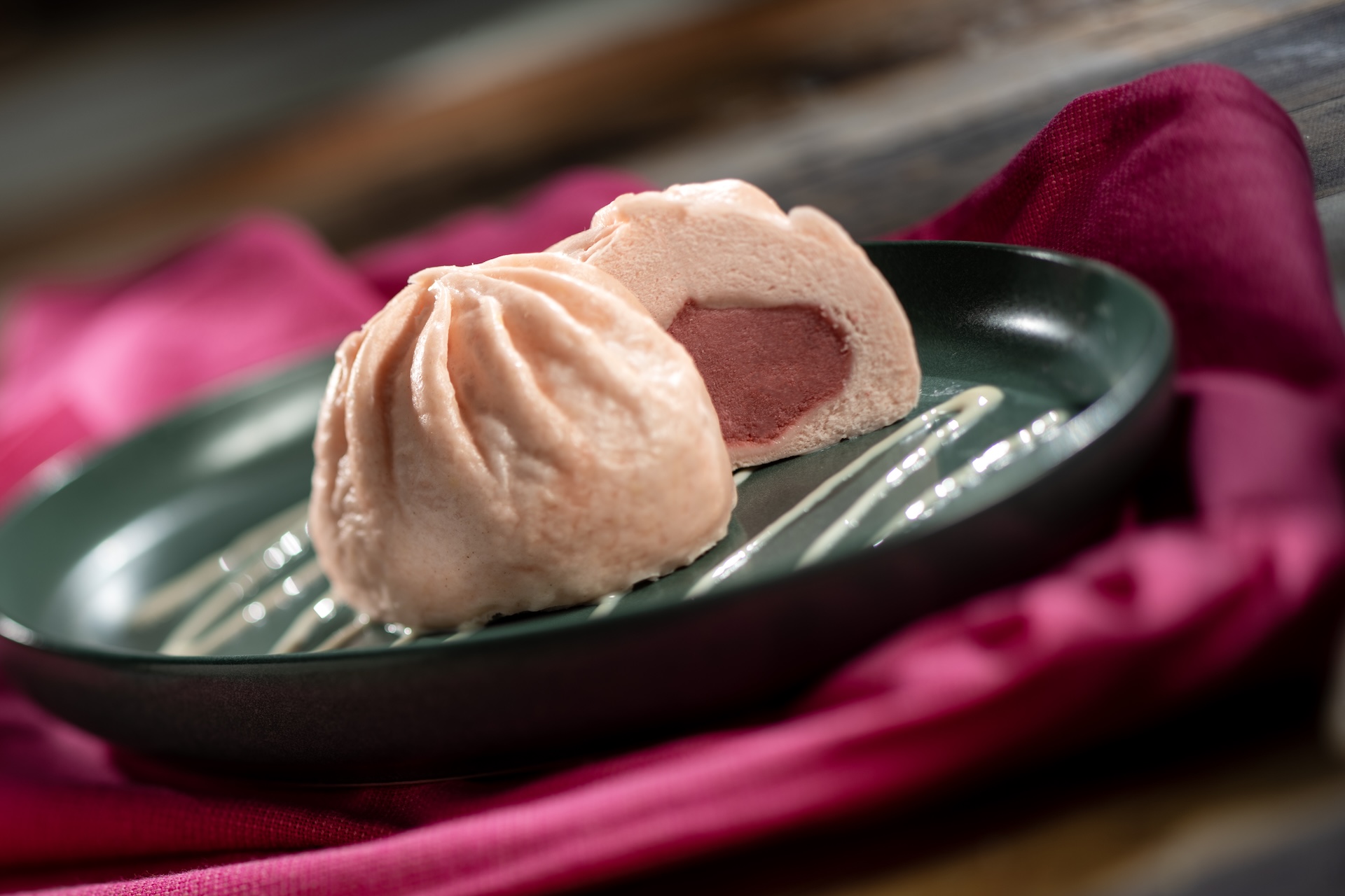 Strawberry Bun: Soft pink dessert bao containing sweet strawberry cream filling finished with a light coconut sauce (New)