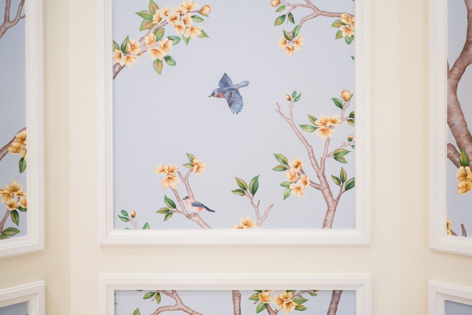 Floral mural with birds on light blue background in a lobby.