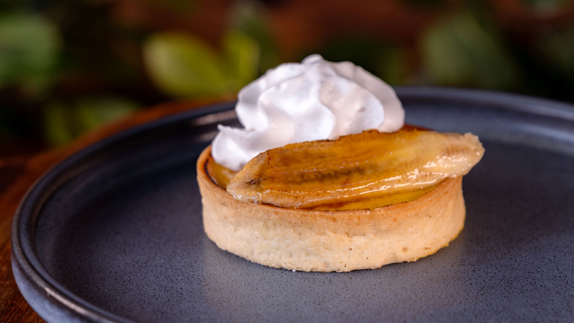 Banana tart topped with whipped cream on a plate.