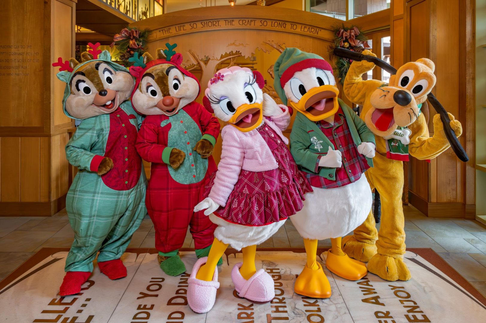 Five Disney characters in festive pajamas pose together indoors.