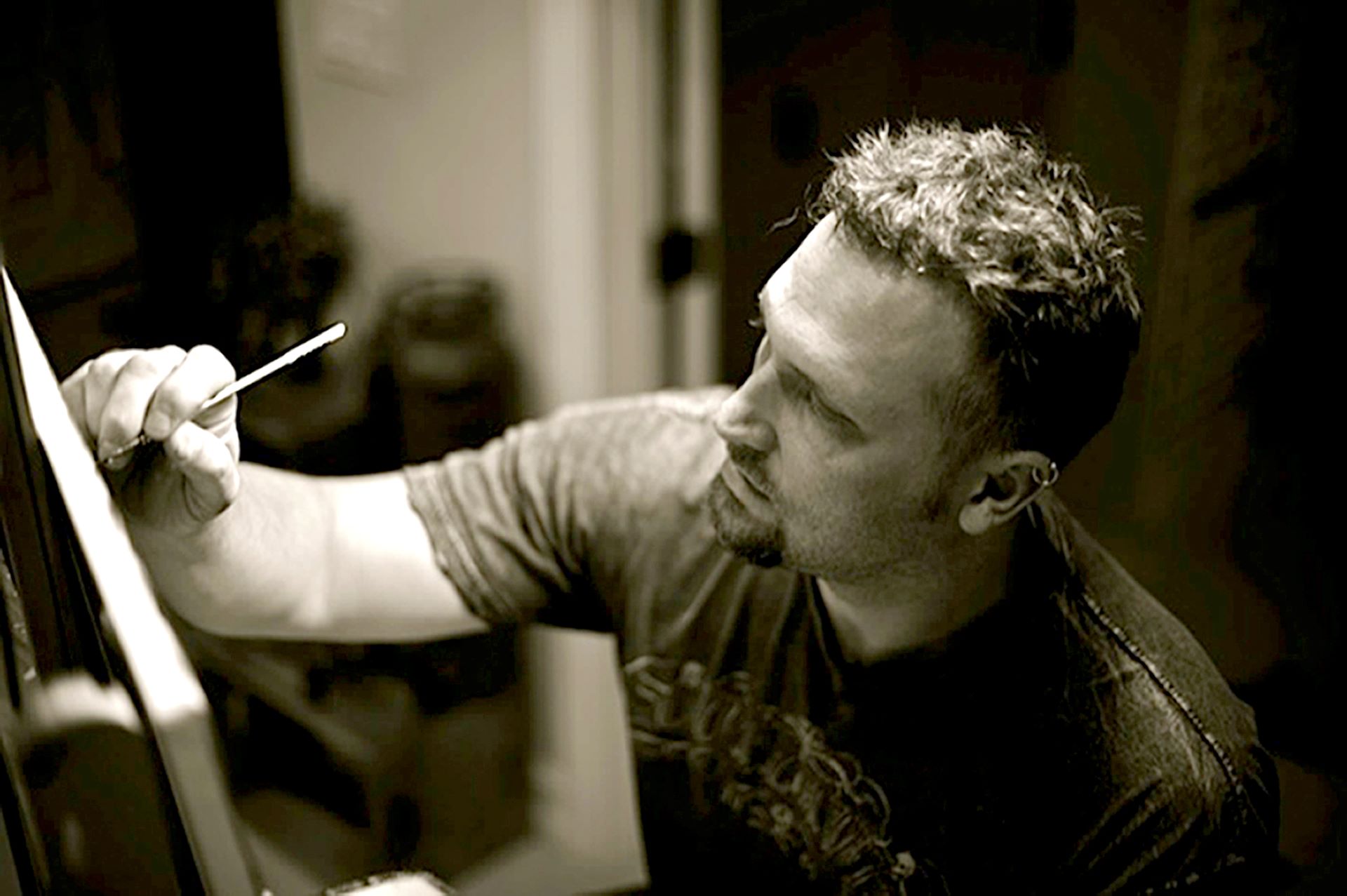 Artist painting on canvas, focusing intently with a brush in hand.