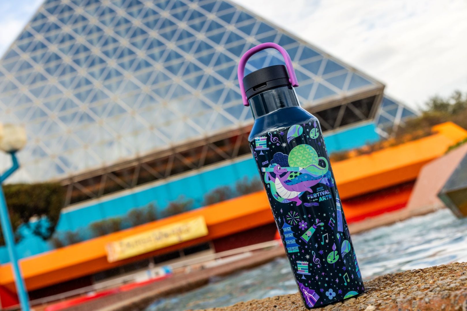 Colorful water bottle with festival design in front of EPCOT building.