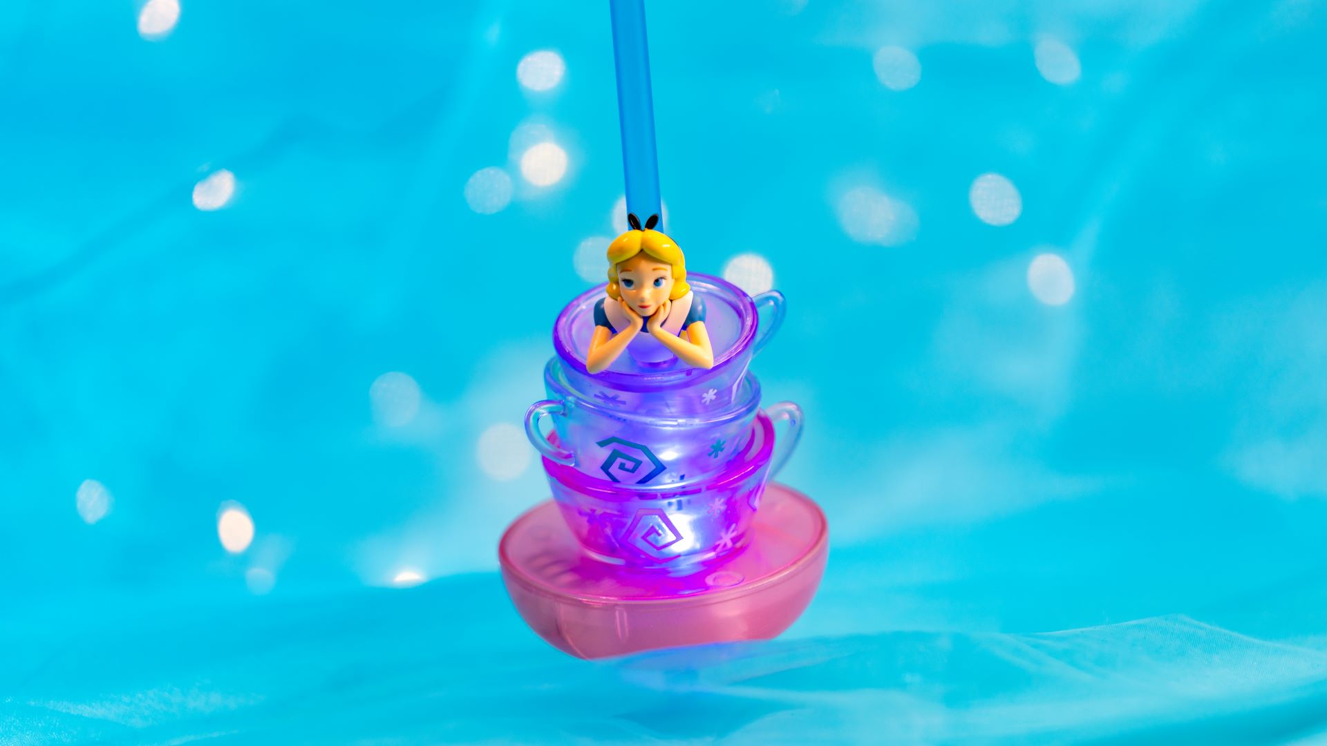 Colorful teacup bottle topper with a character figure against a blue background.