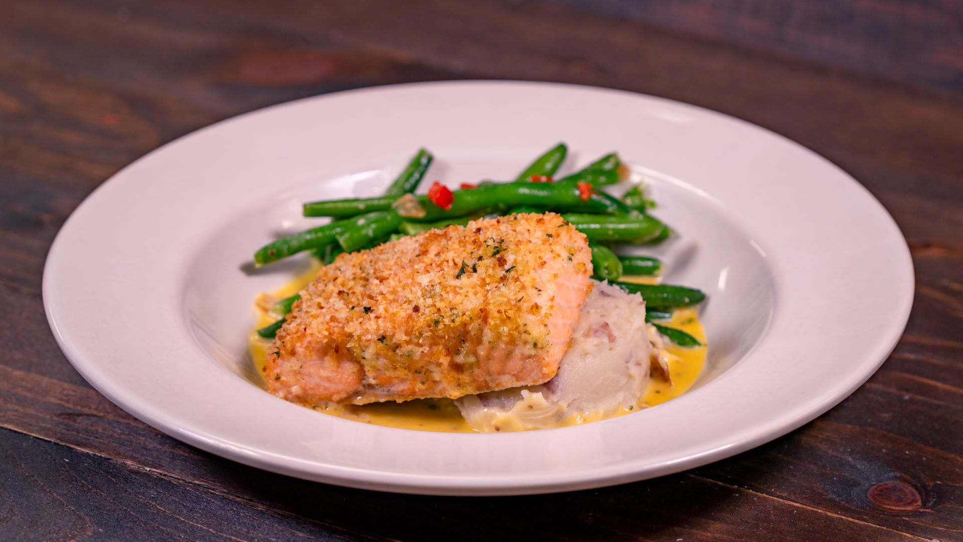 Baked salmon with green beans and mashed potatoes on a white plate.