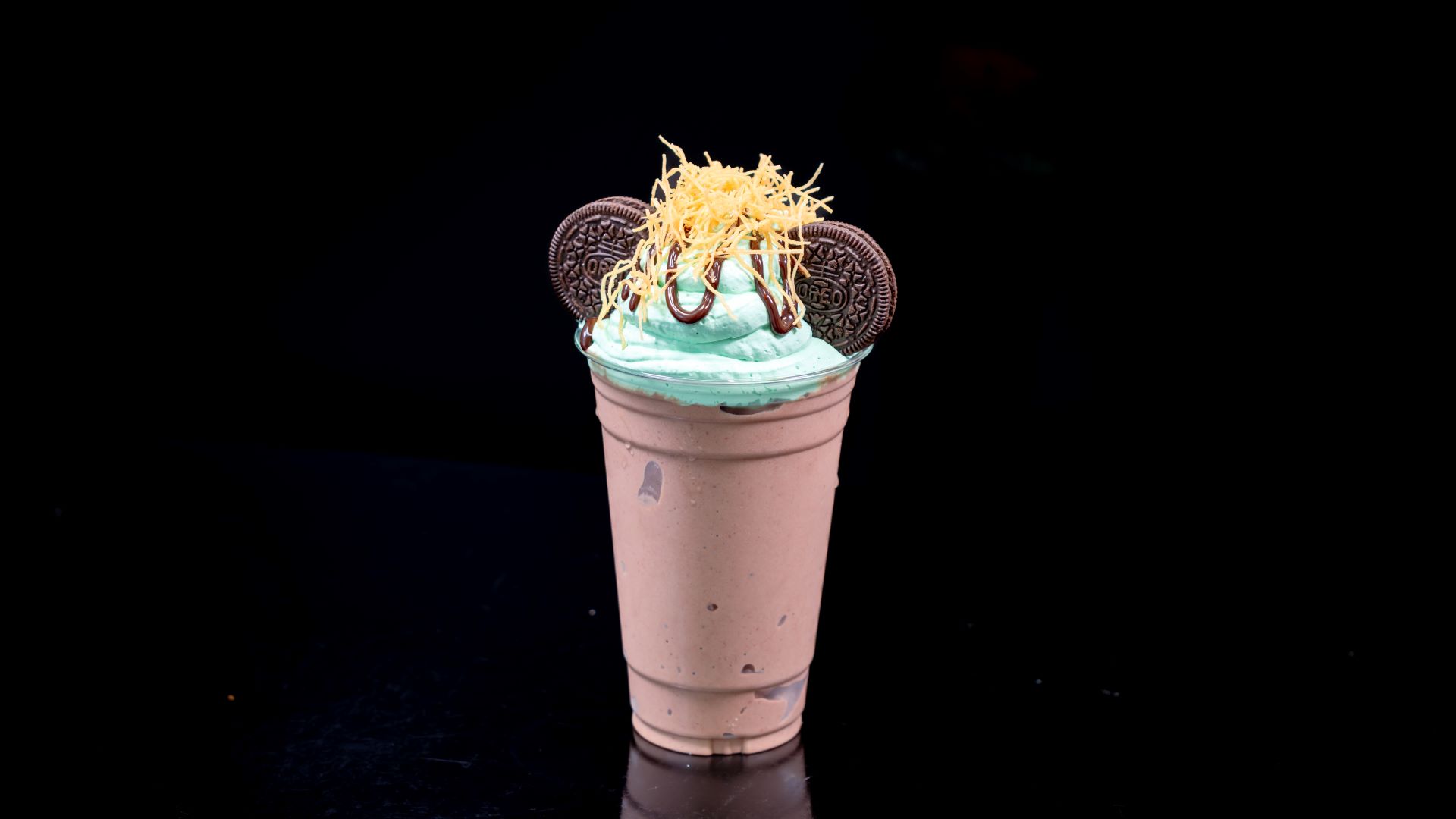 Mint chocolate shake topped with cookies and yellow garnish in a cup.