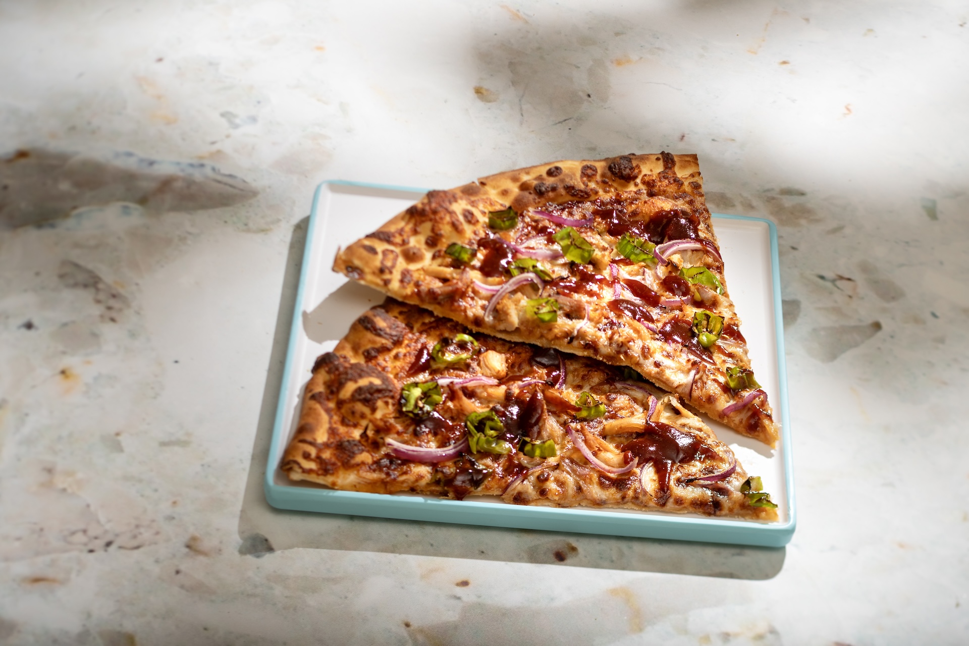 BBQ Chicken Pizza: Two slices of freshly baked pizza topped with smoked chicken, sweet barbecue sauce, cheese blend, peppers, and red onions (New)
