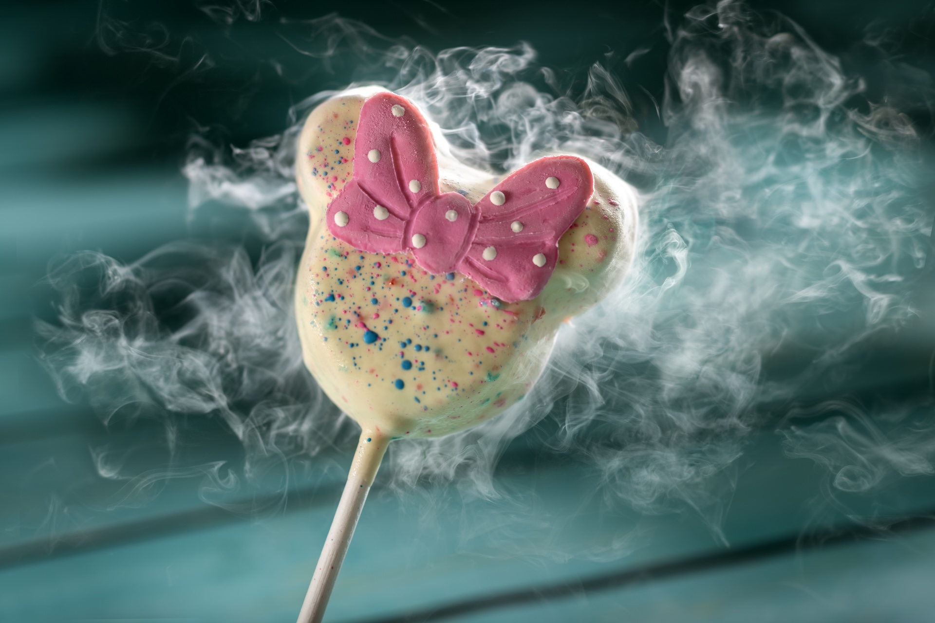 Liquid Nitrogen Minnie Cake Pop with cotton candy sponge cake, white chocolate ganache, and colorful chocolate splats (New)