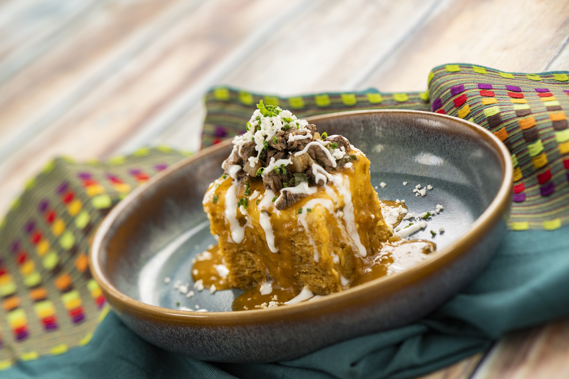 Chilaquiles con Carne: Corn tortillas tossed in salsa ranchera and monterey jack with shaved rib-eye, poblano peppers, onions, queso fresco, and crema mexicana (New)