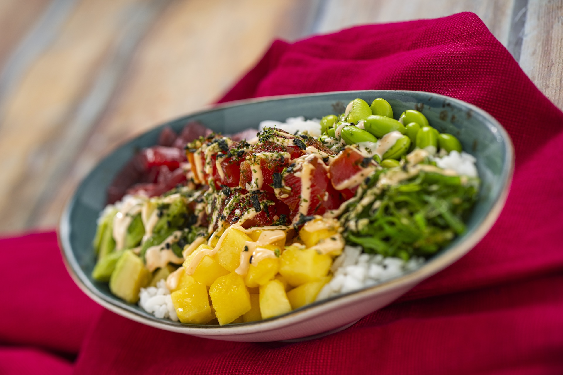 Tuna Poke Bowl with edamame, avocado, mango, pickled red onions, seaweed salad, furikake, and umami sauce on a bed of sticky rice (New)