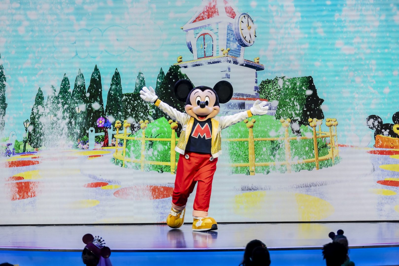 Mickey Mouse in a colorful outfit, surrounded by a vibrant animated background.