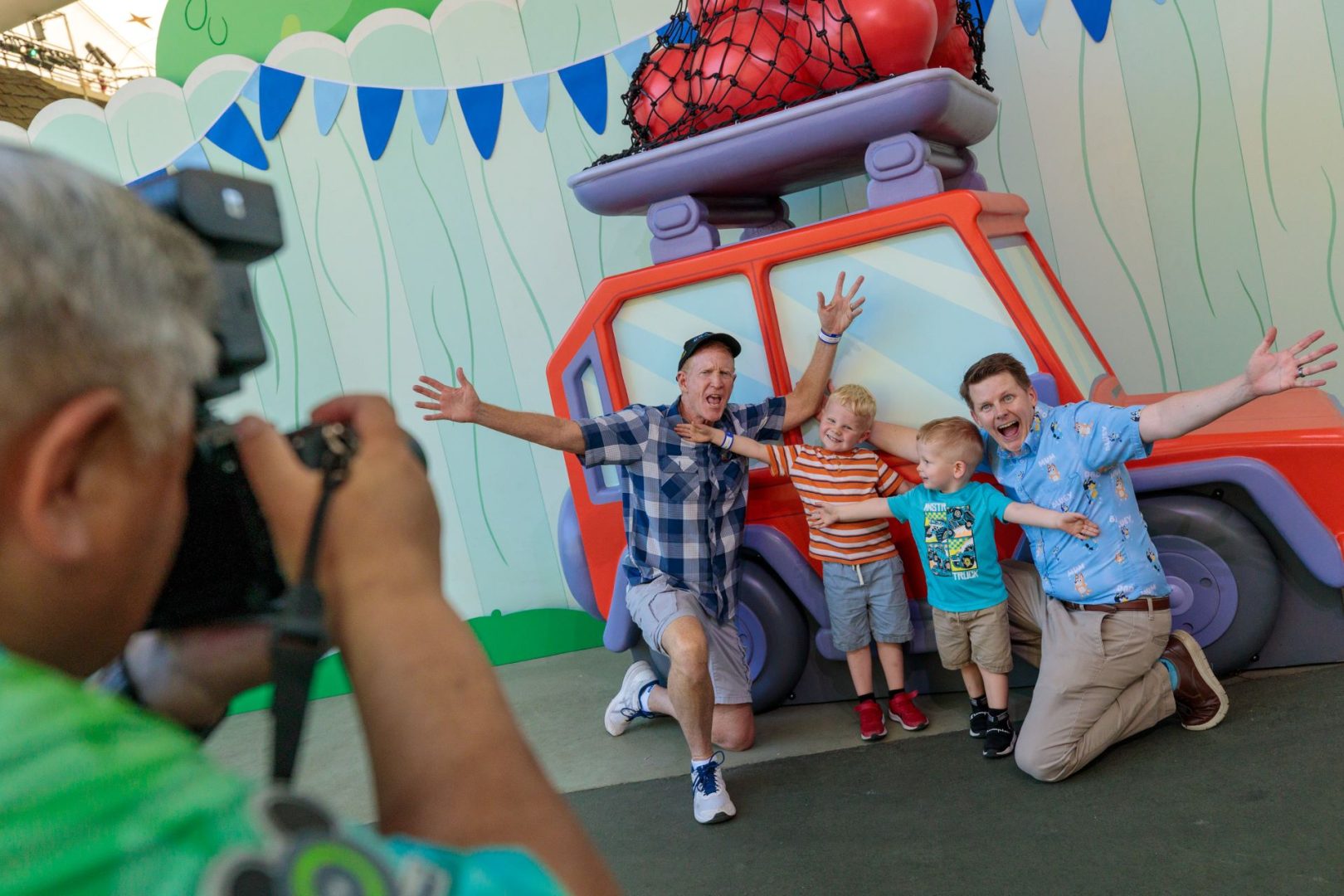 Family posing excitedly in front of a colorful vehicle backdrop at Disneyland.