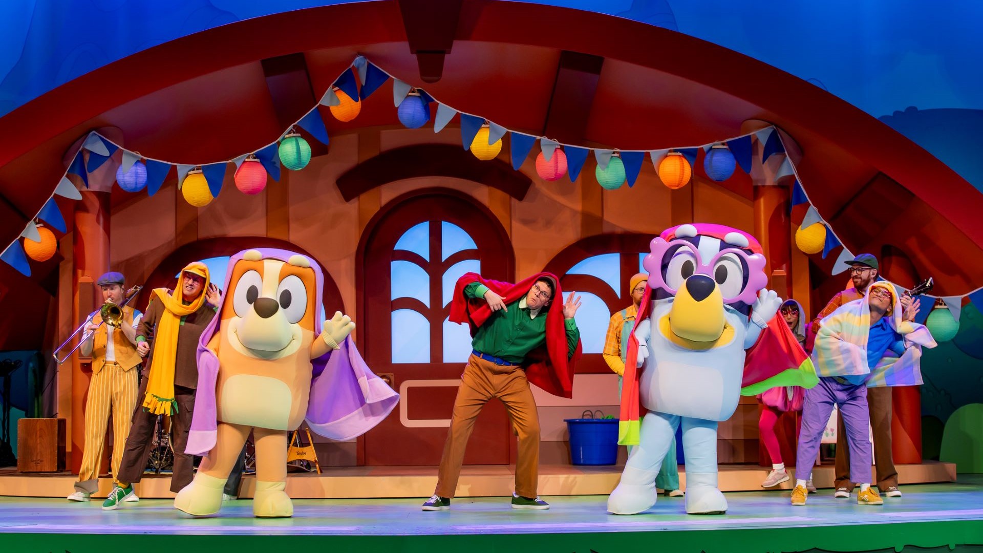 Bluey and characters performing on stage with colorful decorations.
