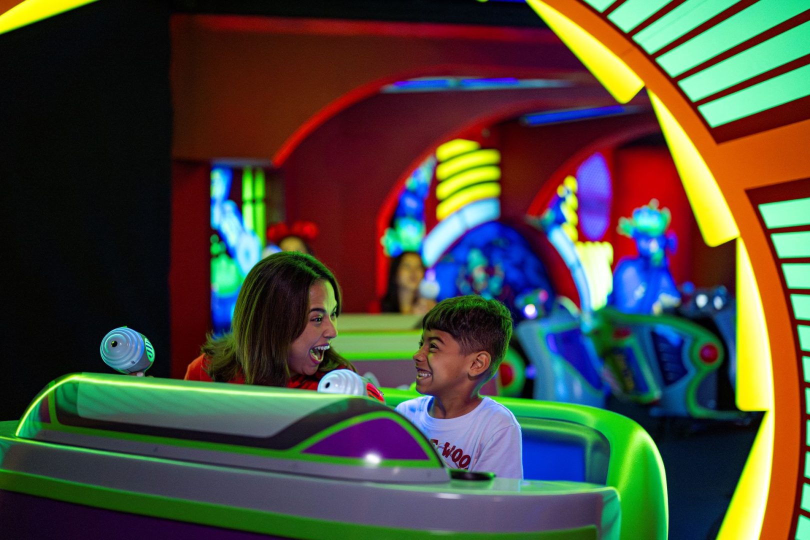 A woman and a boy excitedly enjoy Buzz Lightyear's Space Ranger Spin ride.