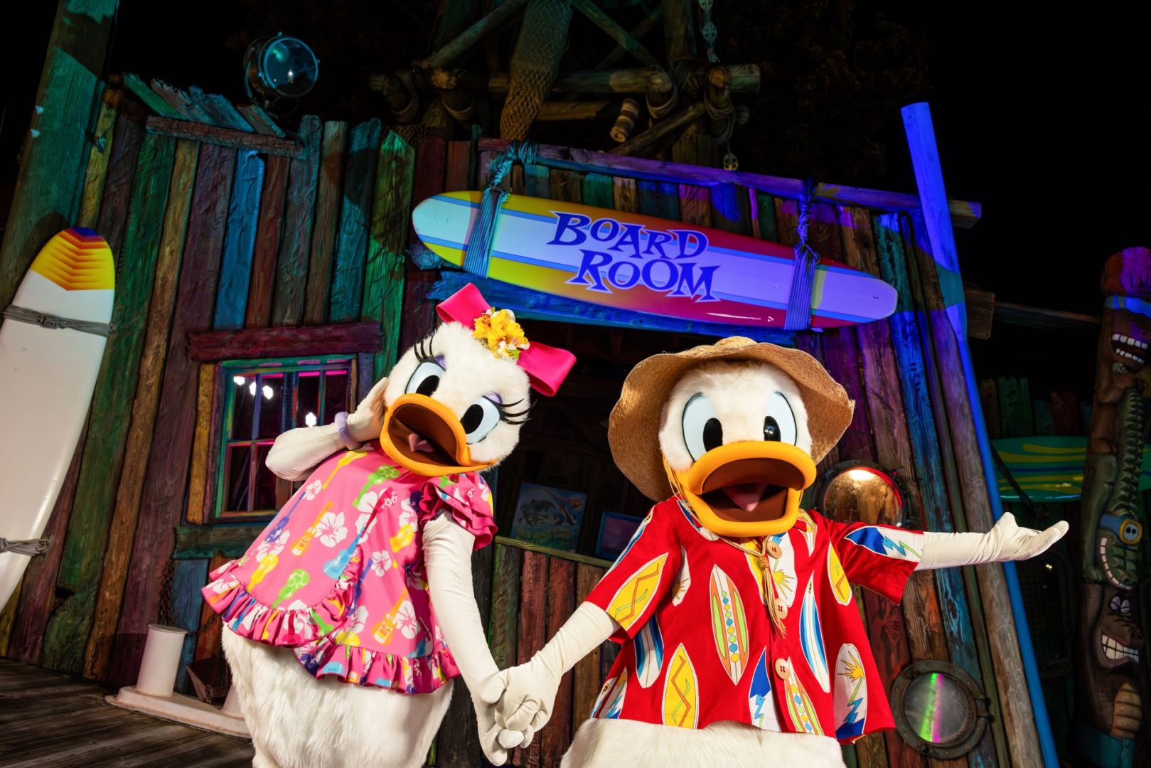 Donald Duck and Daisy Duck in tropical outfits, holding hands at Typhoon Lagoon.