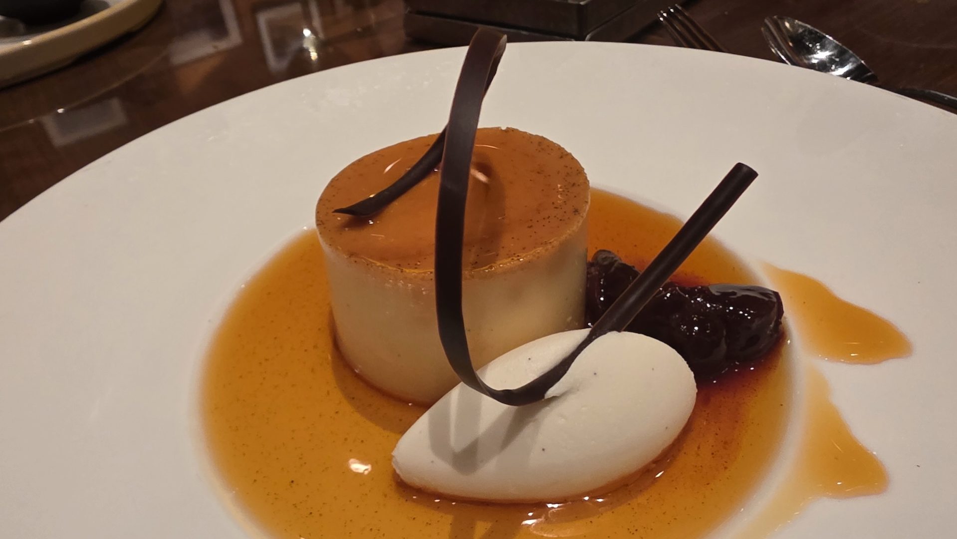 Dessert featuring caramel mousse, cream, and berry compote on a plate.
