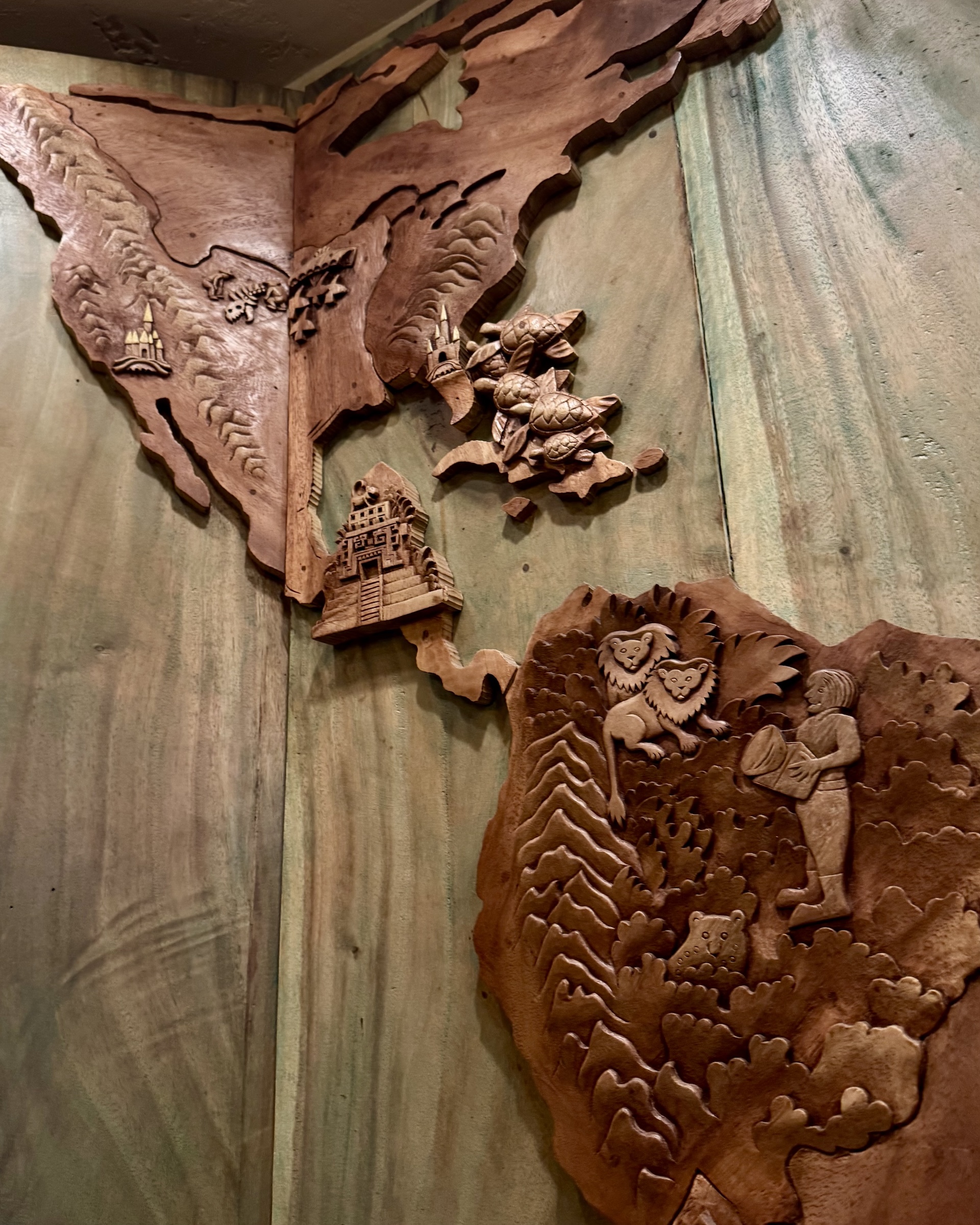 Wooden relief map featuring animals and landmarks, displayed in a restaurant.