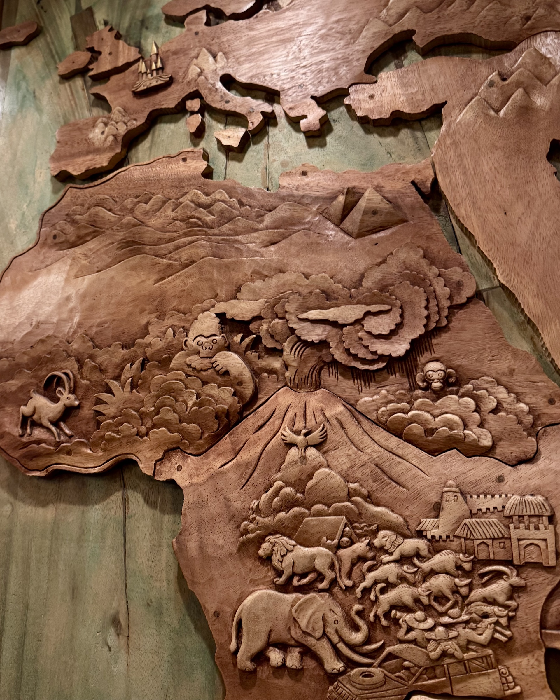 Carved wooden relief map featuring animals and landscapes from Africa and Europe.
