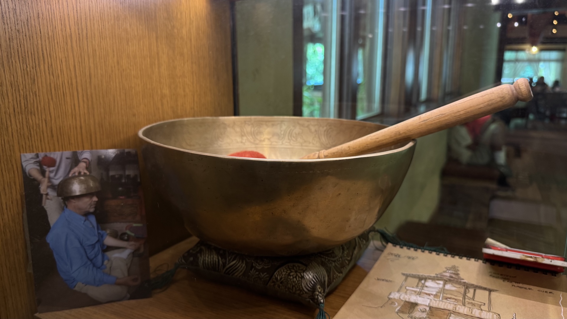 Decorative singing bowl with wooden mallet and a photo nearby.