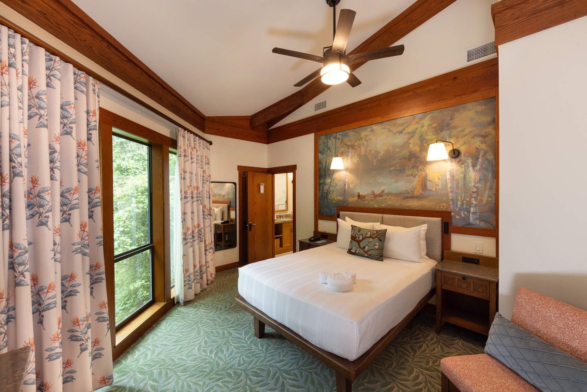 Cozy hotel room with a bed, artwork, and large windows.
