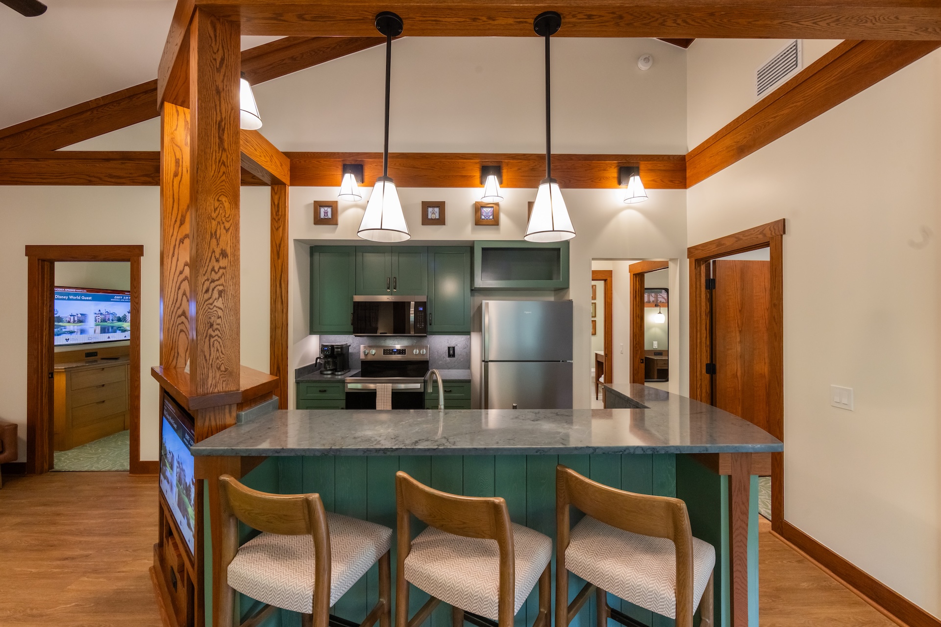 Modern kitchen interior with green cabinets and bar stools.