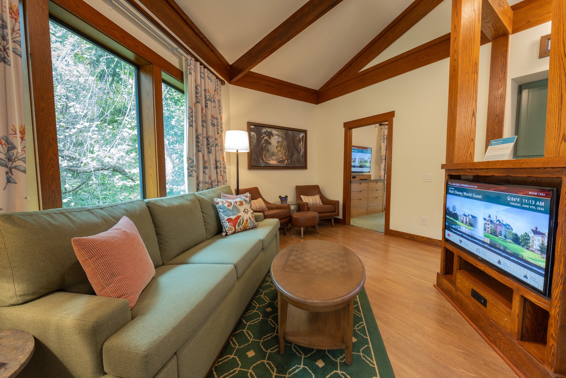Cozy living area with green couch, coffee table, and large windows.