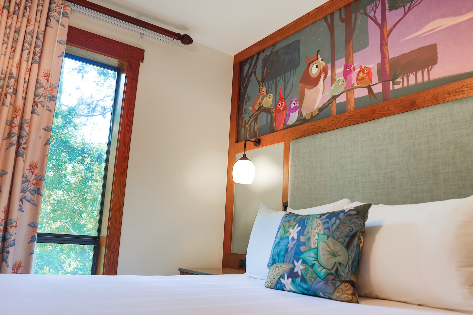 Cozy bedroom featuring a colorful bird mural and floral curtains.