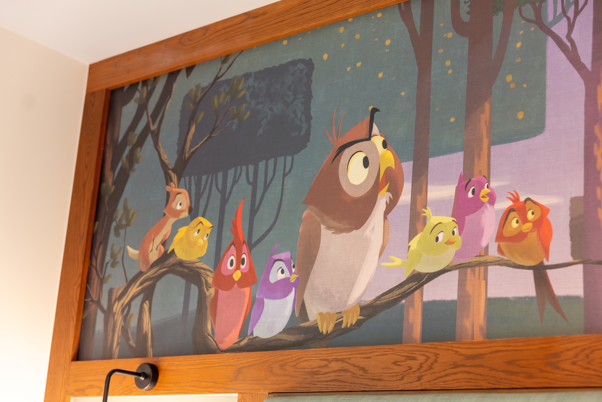 Colorful cartoon birds perched on a branch against a forest backdrop.