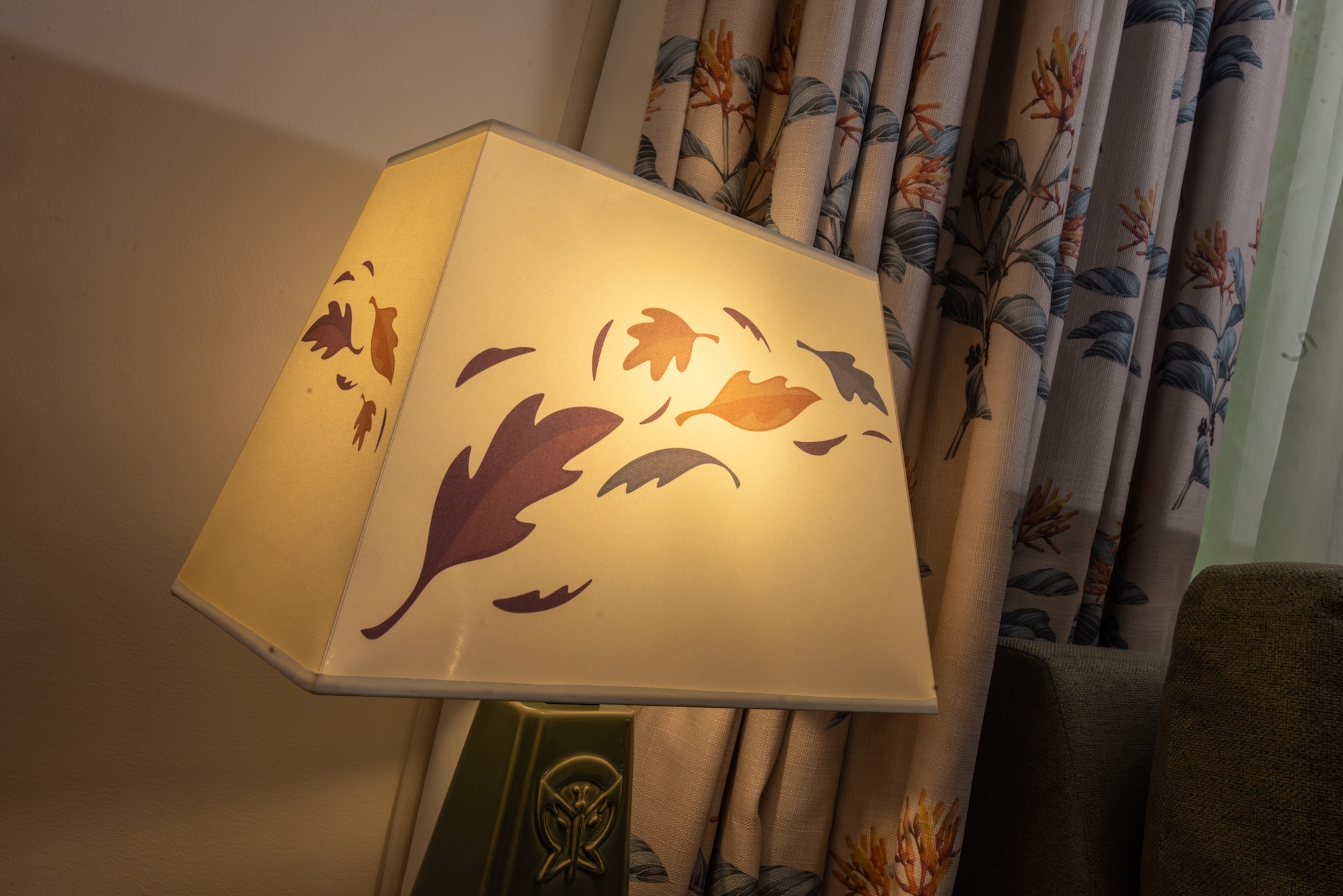 Decorative lamp with leaf patterns next to patterned curtains.