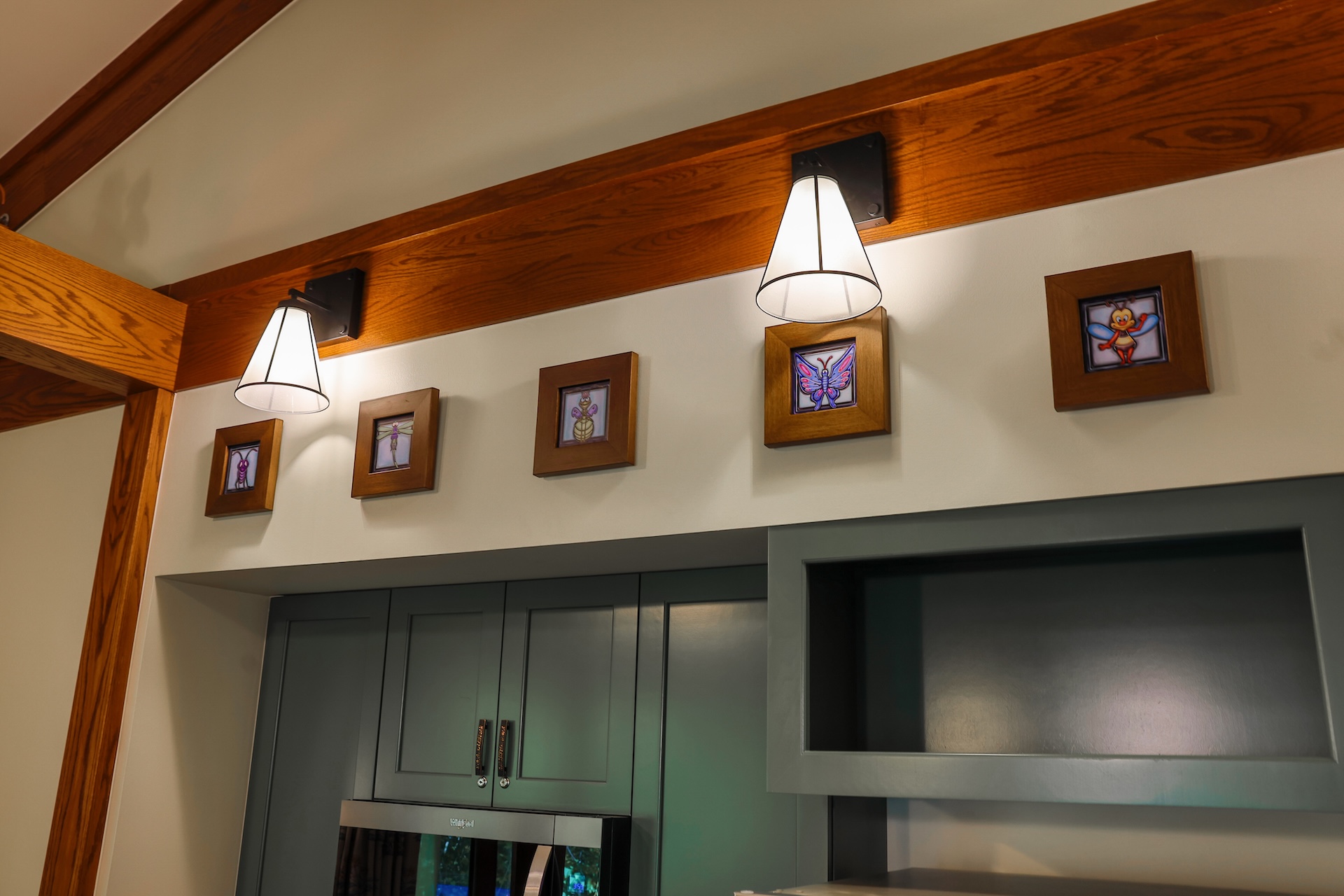 Wall-mounted lights above framed artwork in a modern kitchen setting.