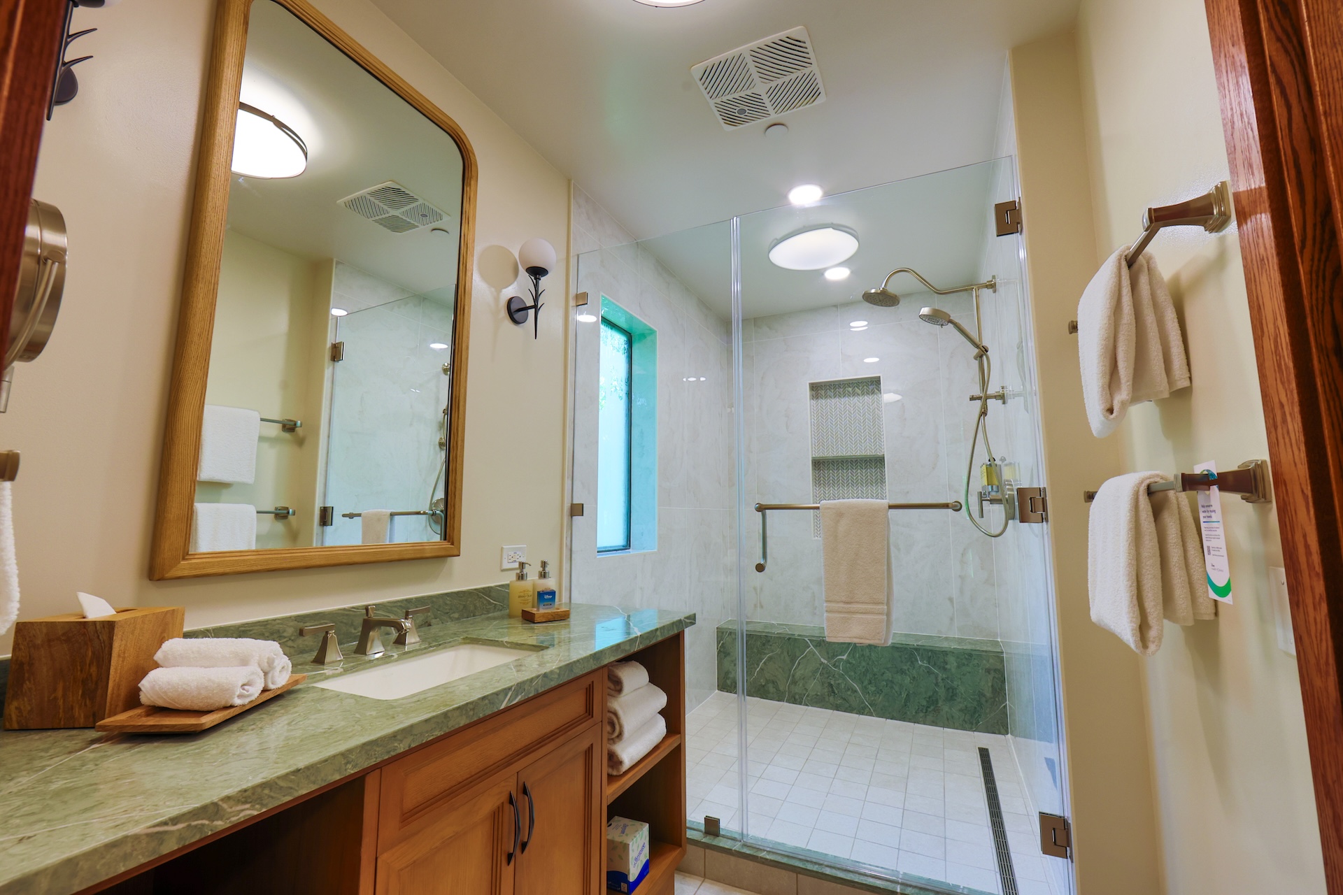 Modern bathroom featuring a glass shower, sink, and green marble accents.